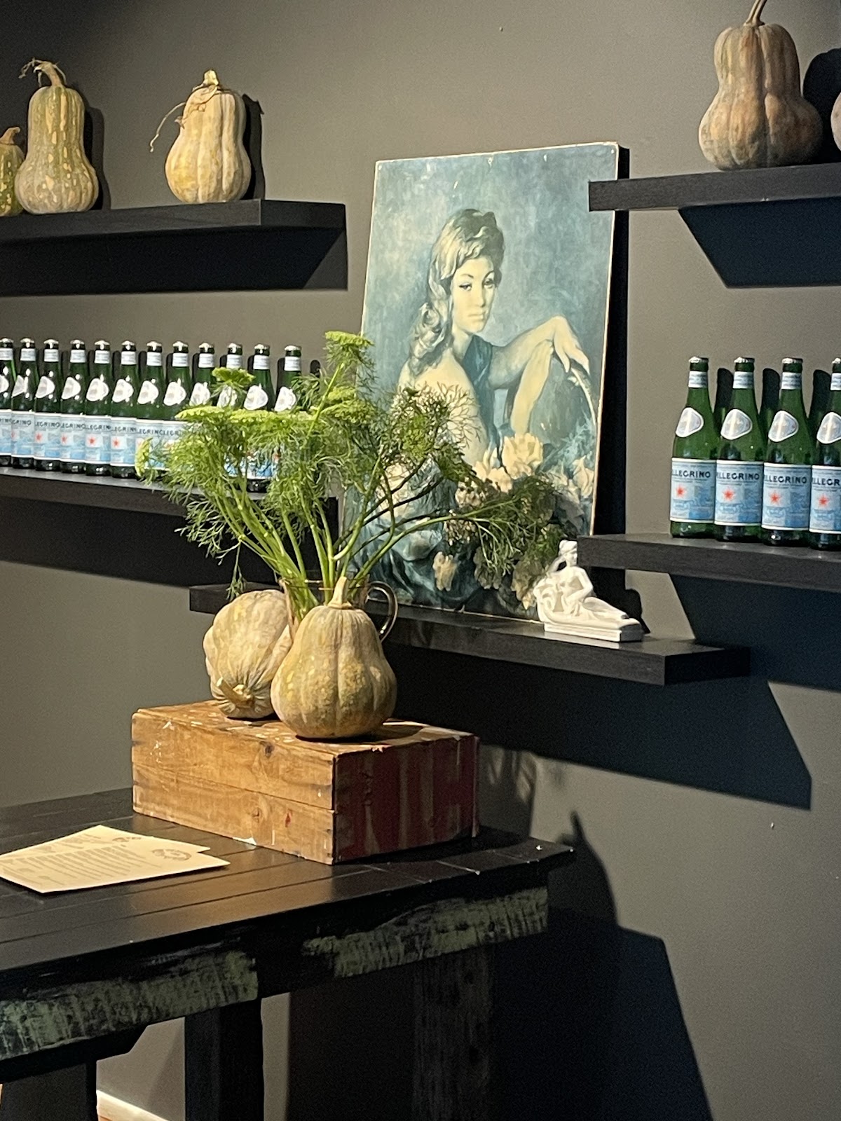 Inside Teakwood Cafe: shelves of gourds, a portrait and fresh flowers against a charcoal wall