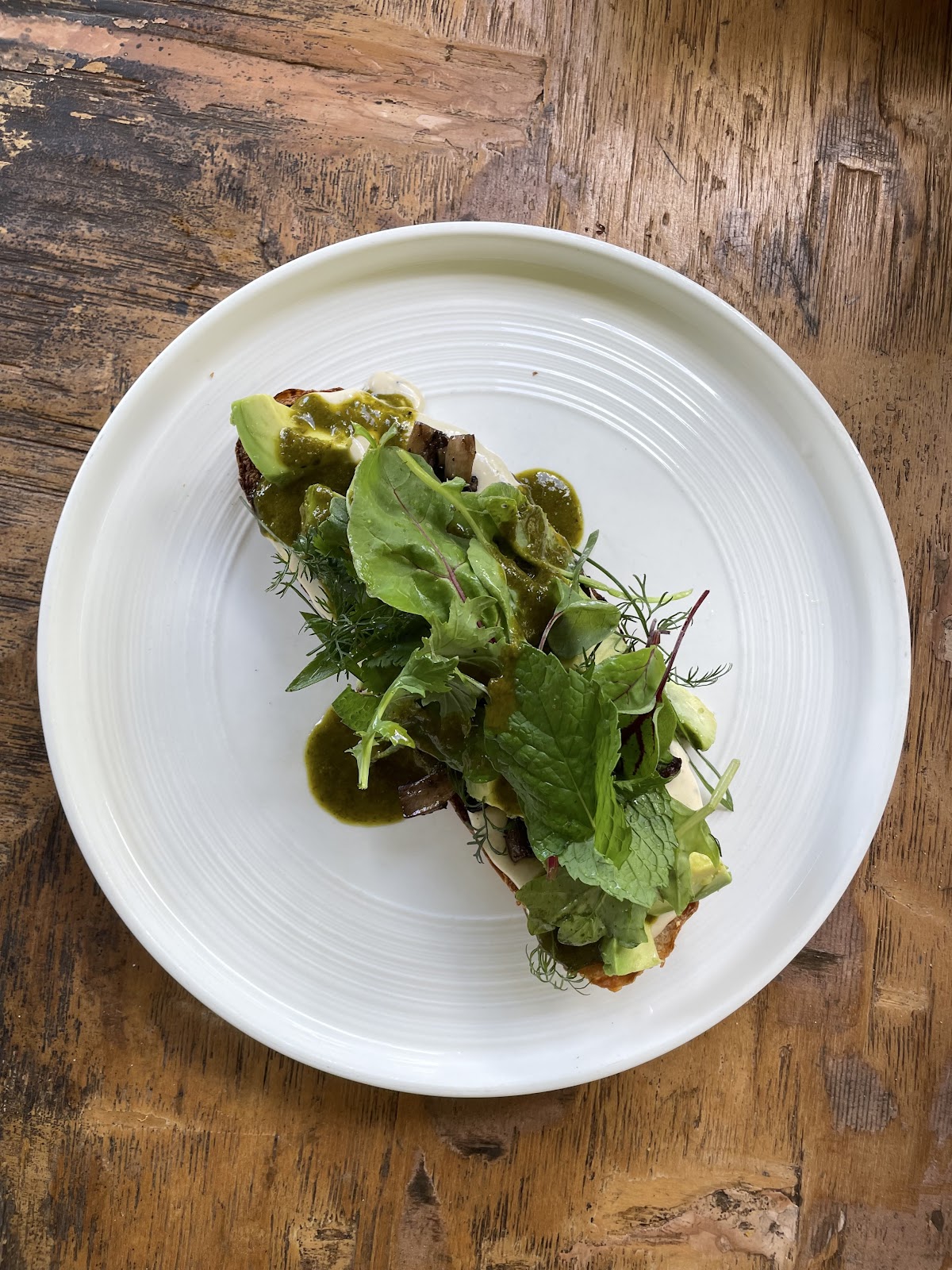 Greens and avocado on toast on a rustic timber table