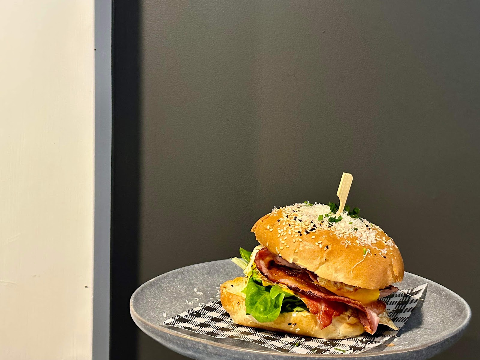 A brioche burger with bacon on gingham paper